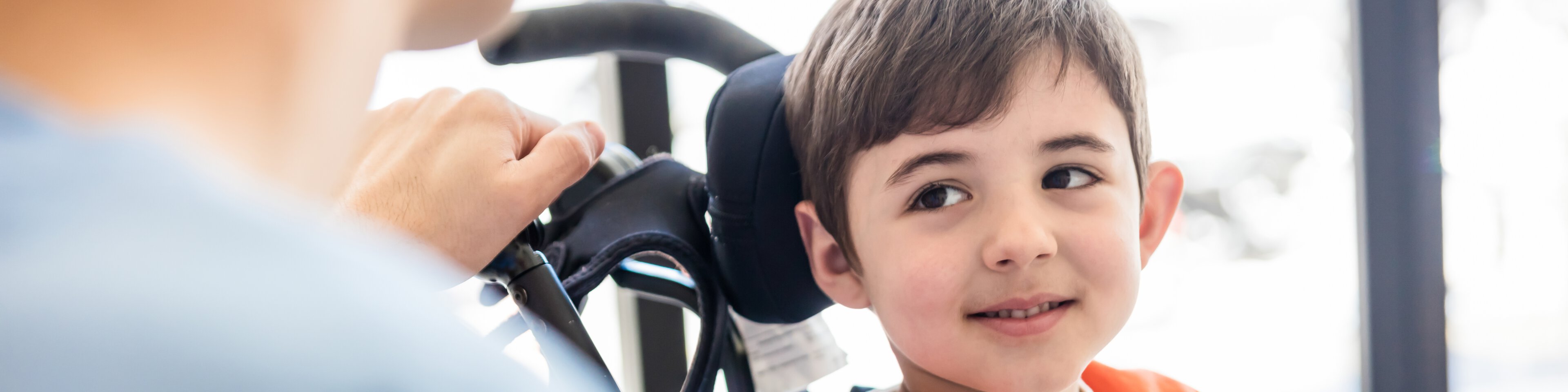 Ein Junge im Rollstuhl lacht in Richtung der Betreuerin | © Hispanolistic - Getty Images
